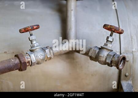 Nahaufnahme von zwei alten Wasserleitungen mit roten runden Zapfhähnen Stockfoto