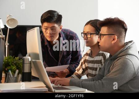 Seriöse Studenten in Brillen testen neues Programm, an dem sie arbeiteten und auf den Computerbildschirm schauten Stockfoto