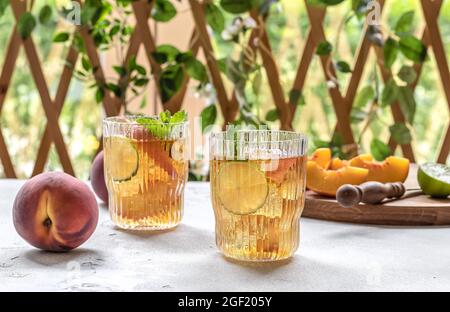 Zwei Gläser mit hausgemachtem Pfirsich-Eistee oder Limonade mit Minze. Sommerliches kaltes Getränk mit reifen Früchten und Eis. . Alkoholfreier Cocktail oder Kombucha. Stockfoto