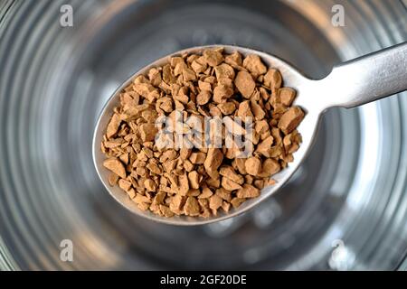 Gefriergetrockneter Instant-Kaffee auf Teelöffel mit Glas-Kaffeetasse Hintergrund. Stockfoto