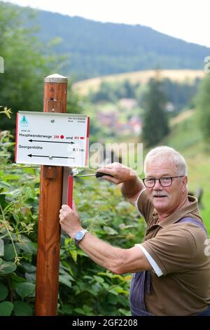 Wildemann, Deutschland. August 2021. Klaus Petersen, der Hauptwegenwärter des Harzklub e.V., schraubt sich einen Wegweiser für einen Wanderweg im Harz. Wandern im Harz wäre sicherlich nur halb so schön, wenn es kein ausgedehntes Wegenetz, Wegweiser an der richtigen Stelle und gute Wanderkarten gäbe! Um dies zu gewährleisten, sind täglich viele ehrenamtliche Mitglieder des Harzklubs im Einsatz. Kredit: Frank May/dpa/Alamy Live Nachrichten Stockfoto