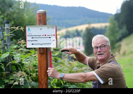 Wildemann, Deutschland. August 2021. Klaus Petersen, der Haupttrailmanager des Harzklub e.V., schraubt sich ein Schild für einen Wanderweg im Harz. Wandern im Harz wäre sicherlich nur halb so schön, wenn es kein ausgedehntes Wegenetz, Wegweiser an der richtigen Stelle und gute Wanderkarten gäbe! Um dies zu gewährleisten, sind täglich viele ehrenamtliche Mitglieder des Harzklubs im Einsatz. Kredit: Frank May/dpa/Alamy Live Nachrichten Stockfoto