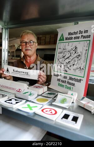 Wildemann, Deutschland. August 2021. Klaus Petersen, der Hauptwegenwärter des Harzklub e.V., zeigt im Lagerraum des Clubhauses diverse Aufkleber für die Schilder der Wanderwege im Harz. Wandern im Harz wäre sicherlich nur halb so schön, wenn es nicht ein ausgedehntes Wegenetz, Wegweiser am richtigen Ort und gute Wanderkarten gäbe! Um dies zu gewährleisten, sind täglich viele ehrenamtliche Mitglieder des Harzklubs im Einsatz. Kredit: Frank May/dpa/Alamy Live Nachrichten Stockfoto