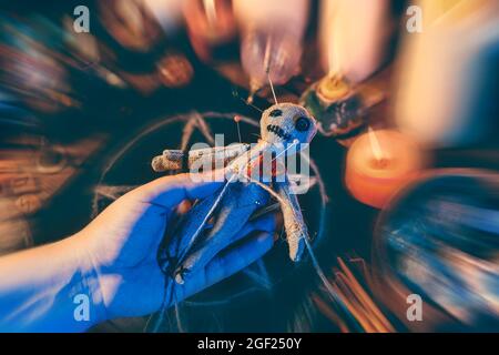 Weibliche Hand hält Voodoo Puppe auf unscharfem Hintergrund. Uralte, dunkle, böse Hexerei der Bestrafung und Rache. Stockfoto