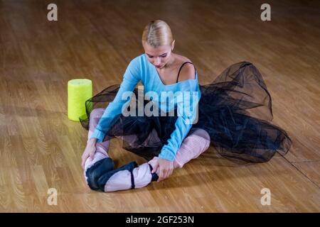Balletttänzerin führt Dehnübungen durch, bevor sie eine Tanzprobe beginnt. Stockfoto