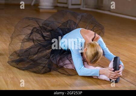 Balletttänzerin führt Dehnübungen durch, bevor sie eine Tanzprobe beginnt. Stockfoto