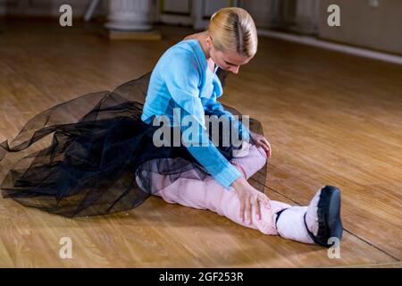 Balletttänzerin führt Dehnübungen durch, bevor sie eine Tanzprobe beginnt. Stockfoto