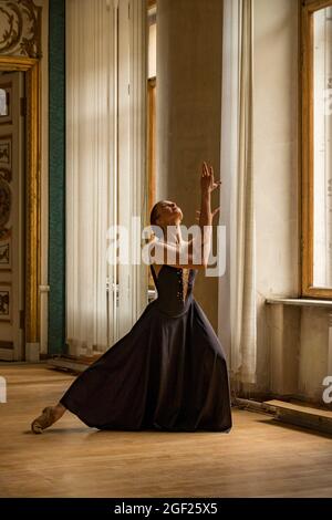 Solo Ballerina tanzt in den Hallen eines alten russischen Palastes, gekleidet in ein kunstvolles Gewand Stockfoto