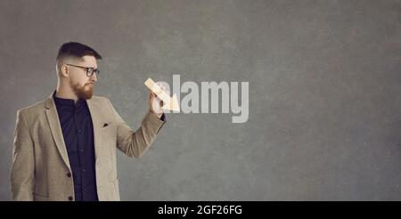 Trauriger Geschäftsmann mit Pfeil, der auf grauen Kopierraum-Hintergrund zeigt Stockfoto