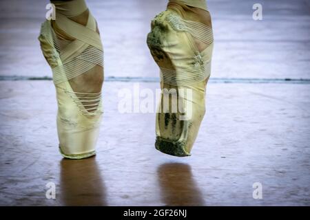 Nahaufnahmen von Ballettschuhen und Tutu einer Tänzerin, die sich vor einer Aufführung in Sankt Petersburg, Russland, dehnt Stockfoto