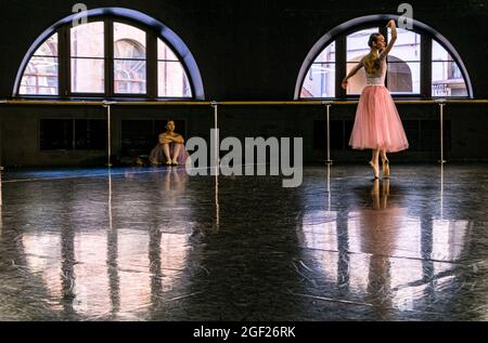 Zwei Ballerinas üben ihre Routine in einer Probenhalle in Sankt Petersburg, wobei ein Tänzer den anderen beobachtet. Stockfoto