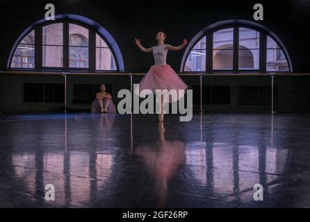 Zwei Ballerinas üben ihre Routine in einer Probenhalle in Sankt Petersburg, wobei ein Tänzer den anderen beobachtet. Stockfoto