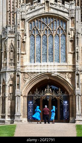 Ein englischer Priester und zwei afrikanische Nonnen am Eingang der christlichen mittelalterlichen Kirche St. Peter in Peterborough, England. Stockfoto