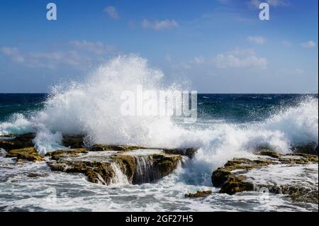 Wilder Teil der Küste mit Wasser, das auf Felsen spritzt, Bonaire, niederländische Karibik. Stockfoto