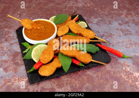 Hähnchen-Satay-Spieße mit Erdnussdippsauce auf einem Schieferbrett Stockfoto