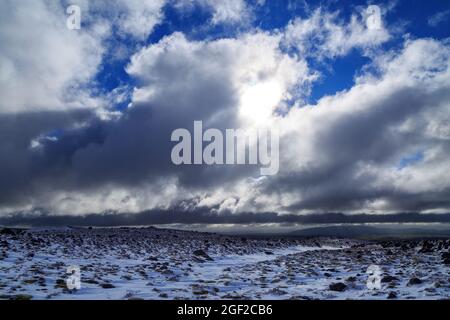 Karge Landschaft aus Schnee und Felsen, mit der Sonne bricht durch die Wolken oben. Mount Ruapehu, Neuseeland Stockfoto