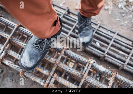 Nahaufnahme eines nicht erkennbaren Bauarbeiters, der Metalltreppen hochgeht, während er schwere Schuhe trägt, Nahaufnahme Stockfoto