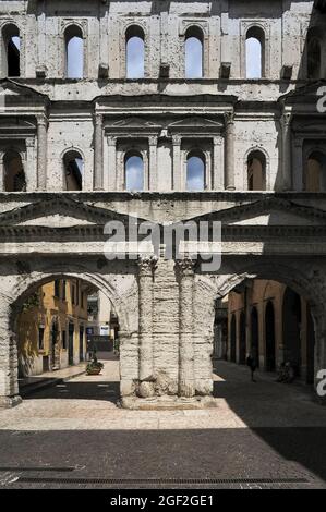 Die Porta Borsari, einst der Haupteingang zum antiken römischen Verona, wurde im 1. Jahrhundert n. Chr. als Porta Iovia nach einem nahe gelegenen Jupiter-Tempel erbaut. Der heutige Name erinnert an die bursarii, mittelalterliche Steuereinnehmer, die ‘„Bursa“-Ledertaschen verwenden, um Zölle auf Waren zu erheben, die in die Stadt ein- oder ausreisen. Unter geriffelten korinthischen Säulen, Giebeln und Bogenfenstern erzählen lateinische Inschriften von der Rekonstruktion im Jahr 265 n. Chr. Die weiße Kalksteinfassade überspannt nun den verkehrsfreien Corso Porta Borsari am Anfang der römischen Straße Via Postumia, die Verona mit Genua und Triest verbindet. Stockfoto