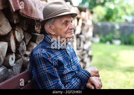 Porträt eines älteren Mannes, der im Garten auf einer Bank sitzt und sich ausruht. Stockfoto