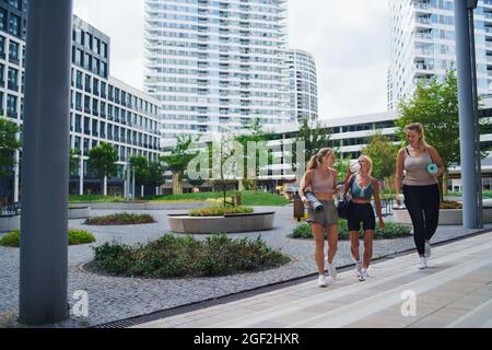Eine Gruppe von jungen und alten Frauen, die nach dem Training in der Stadt im Freien spazieren und sich unterhalten. Stockfoto