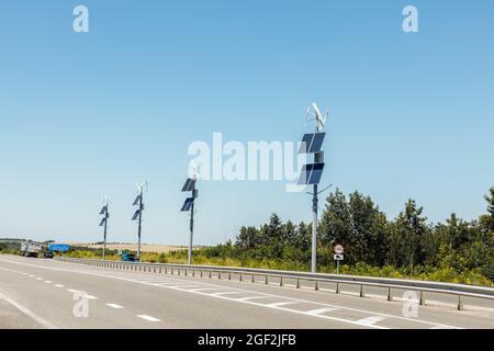 Windturbinen und Sonnenkollektoren, Sonnenkollektoren und Windturbinen gegen blauen Himmel Konzept der erneuerbaren Energie Stockfoto