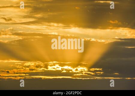 goldene Sonnenstrahlen, die bei Sonnenaufgang durch die Wolken scheinen, Tyndall Effect, Schweiz Stockfoto