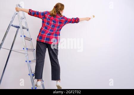 Probleme mit der Sicherheit bei der Lackierung von Hochhausarbeiten. Fallen von einer Leiter, während die Wand gestrichen wird Stockfoto