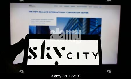 Person, die ein Mobiltelefon mit dem Logo der SkyCity Entertainment Group Limited auf dem Bildschirm vor der Webseite hält. Konzentrieren Sie sich auf die Telefonanzeige. Stockfoto