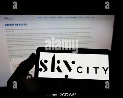 Person, die Mobiltelefon mit dem Logo der Firma SkyCity Entertainment Group Limited auf dem Bildschirm vor der Business-Webseite hält. Konzentrieren Sie sich auf die Telefonanzeige. Stockfoto