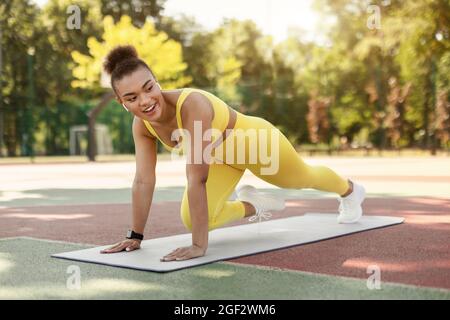 Schwarze Fröhliche Frau Macht Cross Body Mountain Kletterer Übung Stockfoto