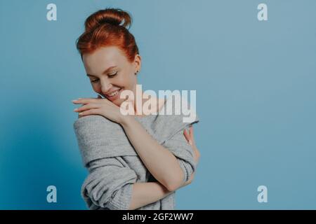 Junge schöne romantische rothaarige Frau trägt Strickpullover umarmt sich mit Vergnügen Stockfoto