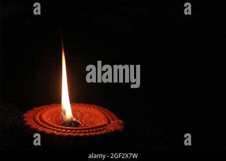 Eine beleuchtete Diya- oder herkömmliche Öllampe, die bei Diwali mit schwarzem Hintergrund leuchtet. Stockfoto