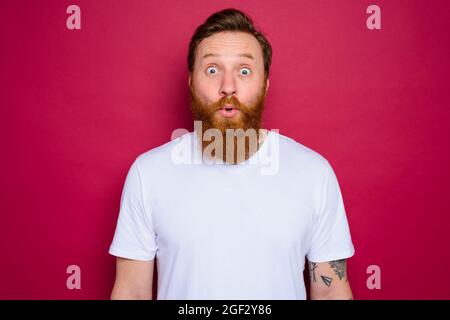 Staunender isolierter Mann mit Bart und weißem T-Shirt Stockfoto