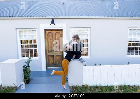 Bruder und Schwester vor ihrem Haus kitzeln sich gegenseitig Stockfoto