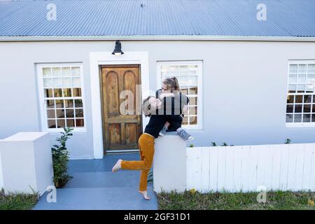 Bruder und Schwester vor ihrem Haus kitzeln sich gegenseitig Stockfoto