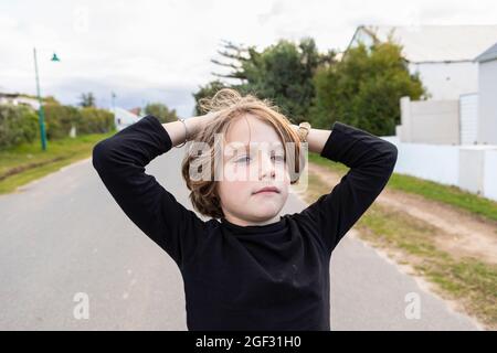 Achtjähriger Junge, Hände auf dem Kopf, Porträt Stockfoto