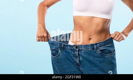 Nahaufnahme Von Skinny Fit Woman, Die Große, Lockere Jeans Zieht Stockfoto