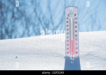 Das Thermometer liegt auf dem Schnee und zeigt ein Negativ Temperatur in kaltem Wetter am blauen Himmel.Meteorologische Bedingungen mit Niedrige Luft und Umgebungs t Stockfoto