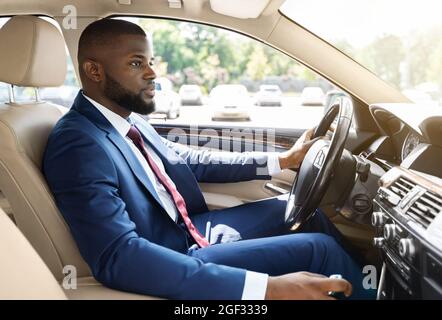 Selbstbewusster afro-amerikanischer Geschäftsmann, der Auto ins Büro fährt Stockfoto