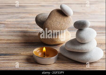 Schöne Zen-Komposition mit Steinen und brennende Kerze auf schäbigen Holzhintergrund Stockfoto