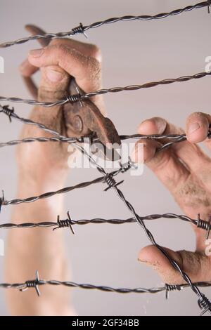 Hände greifen der Stacheldraht im Zeichen weg mit dem weißen Hintergrund zu laufen Stockfoto