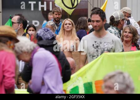 Ein Demonstrator mit strategisch platzierten Aufklebern trifft die Menge während eines Protestes von Mitgliedern von Extinction Rebellion auf der St Martin's Lane im Zentrum von London, zu Beginn eines geplanten zweiwöchigen Aktionsauftritts der Protestgruppe zum Klimawandel. Bilddatum: Montag, 23. August 2021. Stockfoto