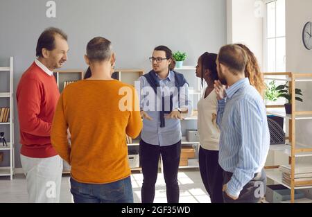 Eine Gruppe von glücklichen und vielfältigen Menschen führt informelle Gespräche in einem modernen Büro Stockfoto