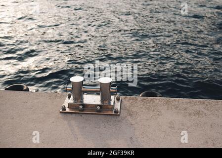 Metallbollard für Boote und Schiffe auf dem Kai über dem Meer und Sonnenuntergang Hintergrund aus nächster Nähe. Seeküsten mit Ausrüstung für das Jagen an der Küste. Reise Stockfoto