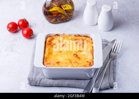 Moussaka mit Fleisch, Auberginen, Tomaten, Kartoffeln, Bechamelsauce und Käse auf einem weißen Teller. Traditionelles griechisches Gericht. Nahaufnahme. Stockfoto