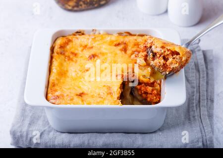 Moussaka mit Fleisch, Auberginen, Tomaten, Kartoffeln, Bechamelsauce und Käse auf einem weißen Teller. Traditionelles griechisches Gericht. Nahaufnahme. Stockfoto