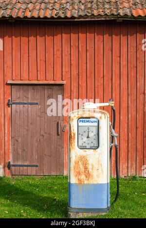 Alte rostige Benzinpumpe durch einen roten Schuppen Stockfoto