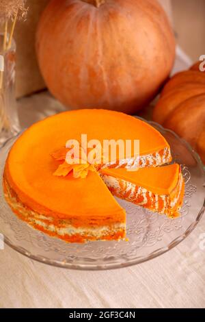 Hausgemachter Hüttenkäse und Kürbisauflauf mit Mohnsamen und Orange auf einem Glasständer auf dem Tisch mit Kürbissen Stockfoto