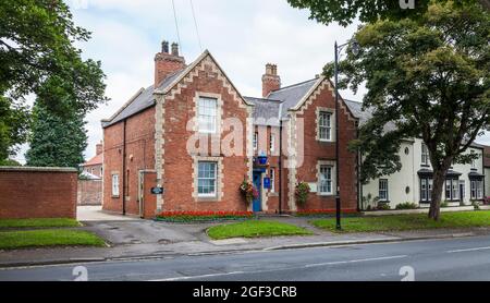 Eine ländliche Polizeidienststelle in Sedgefield, Co Durham, England, Großbritannien mit einer bunten Blütenpracht schmücken die Fassade Stockfoto