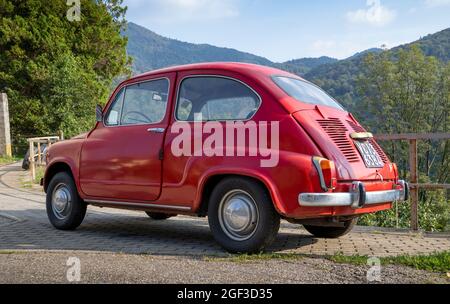 Fiat 600, kleines rotes italienisches Oldtimer, das auf einer Bergstraße geparkt ist Stockfoto